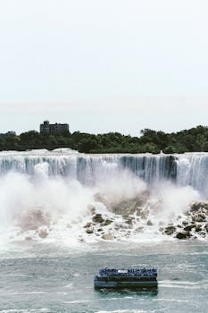 Tourist boat approaching the stunning Falls with lush green surroundings.