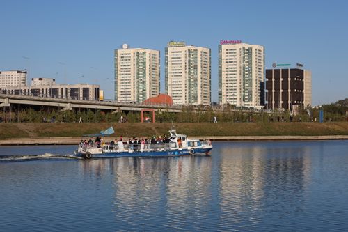Free Ferry boat sailing on a river with modern buildings in the background, capturing urban life. Stock Photo