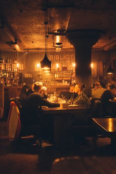 Groups enjoying a relaxed night at a warmly lit restaurant, creating a cozy atmosphere.