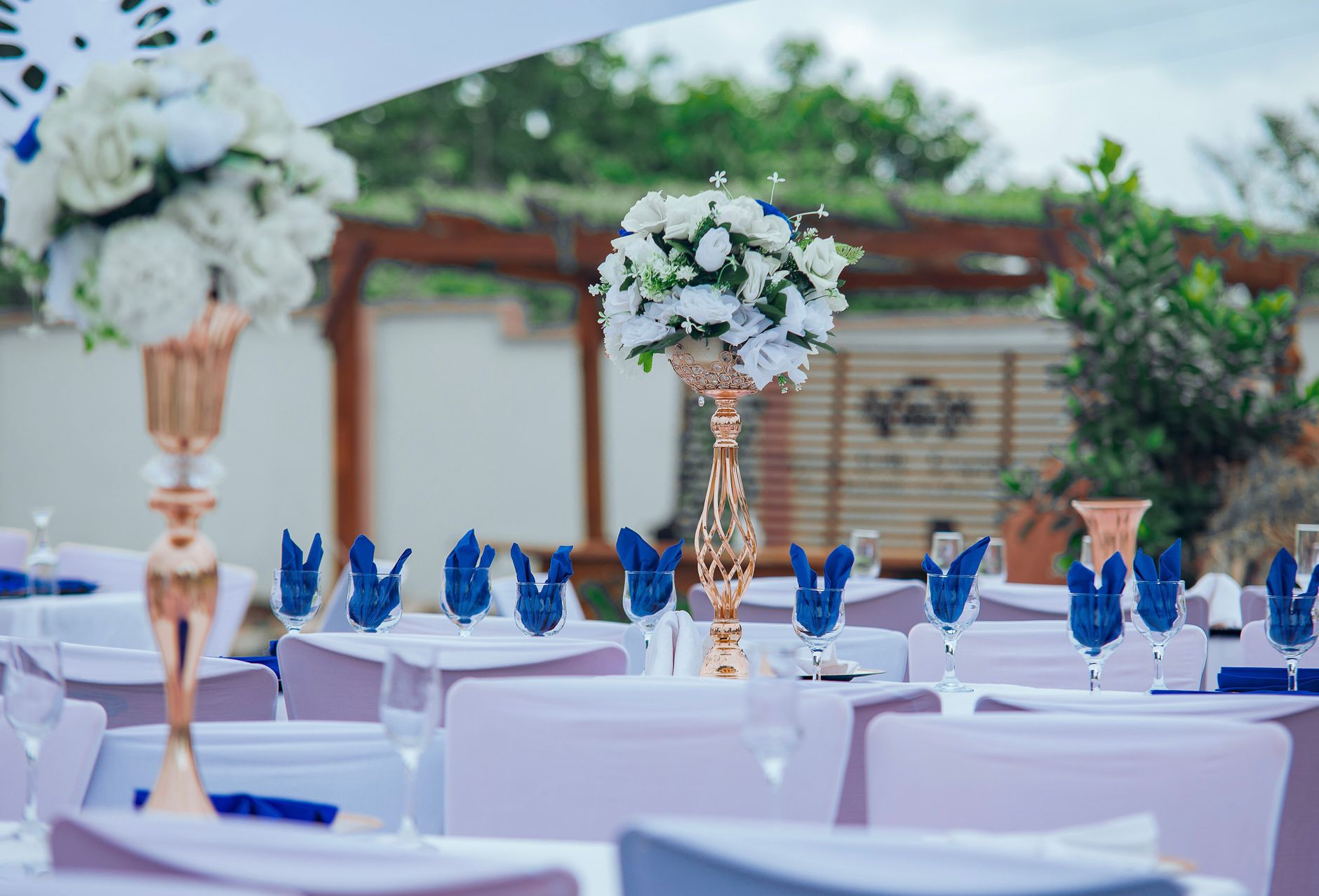 A beautifully decorated outdoor dinner setting with white flowers and blue accents.