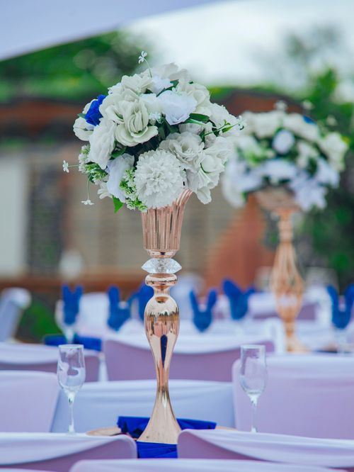 Free Beautiful white and blue flower arrangement in a vase at an outdoor wedding setup. Stock Photo