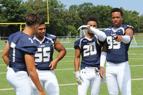 Four Football Players Standing on Green Grass Field