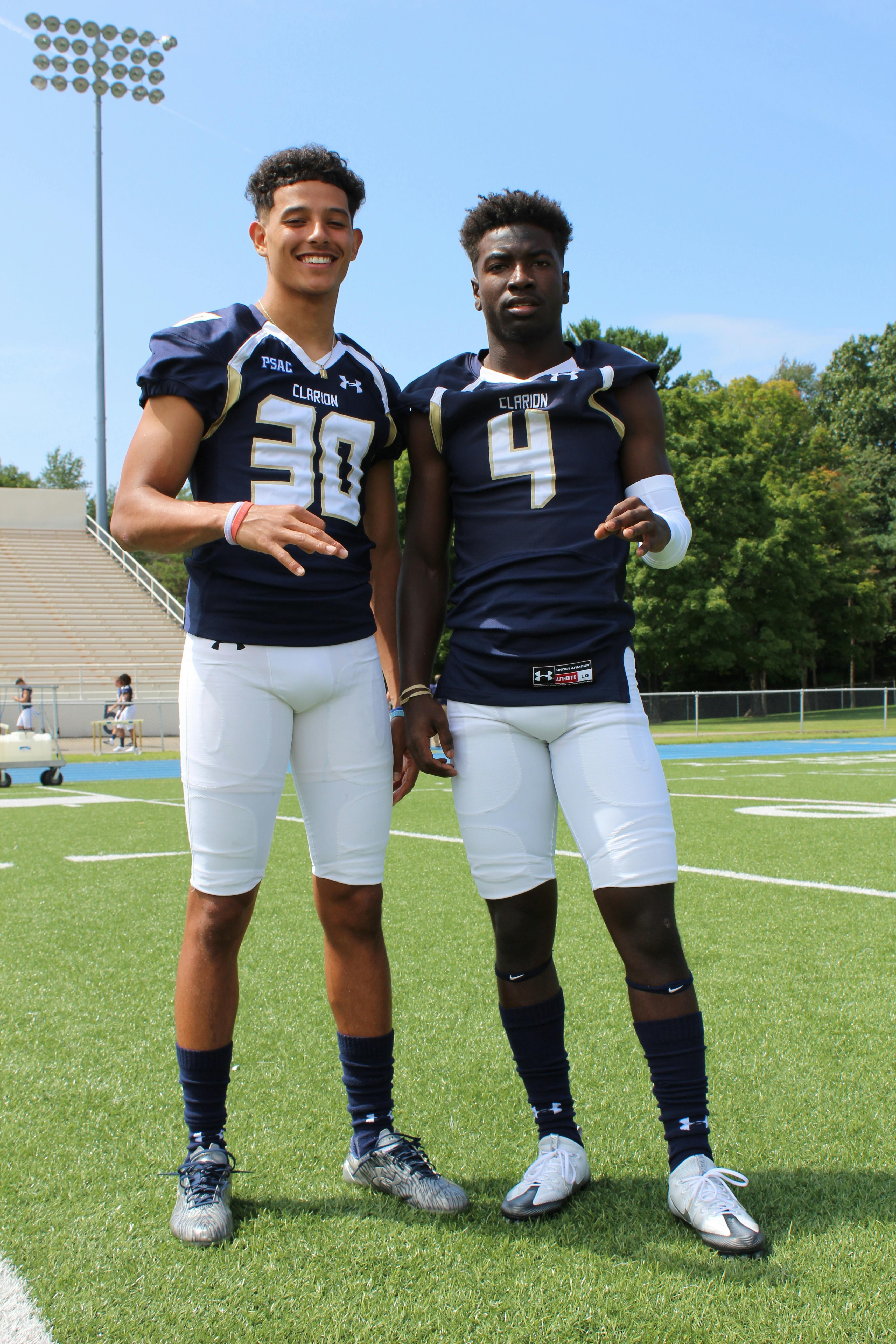 two football players taking picture on football field