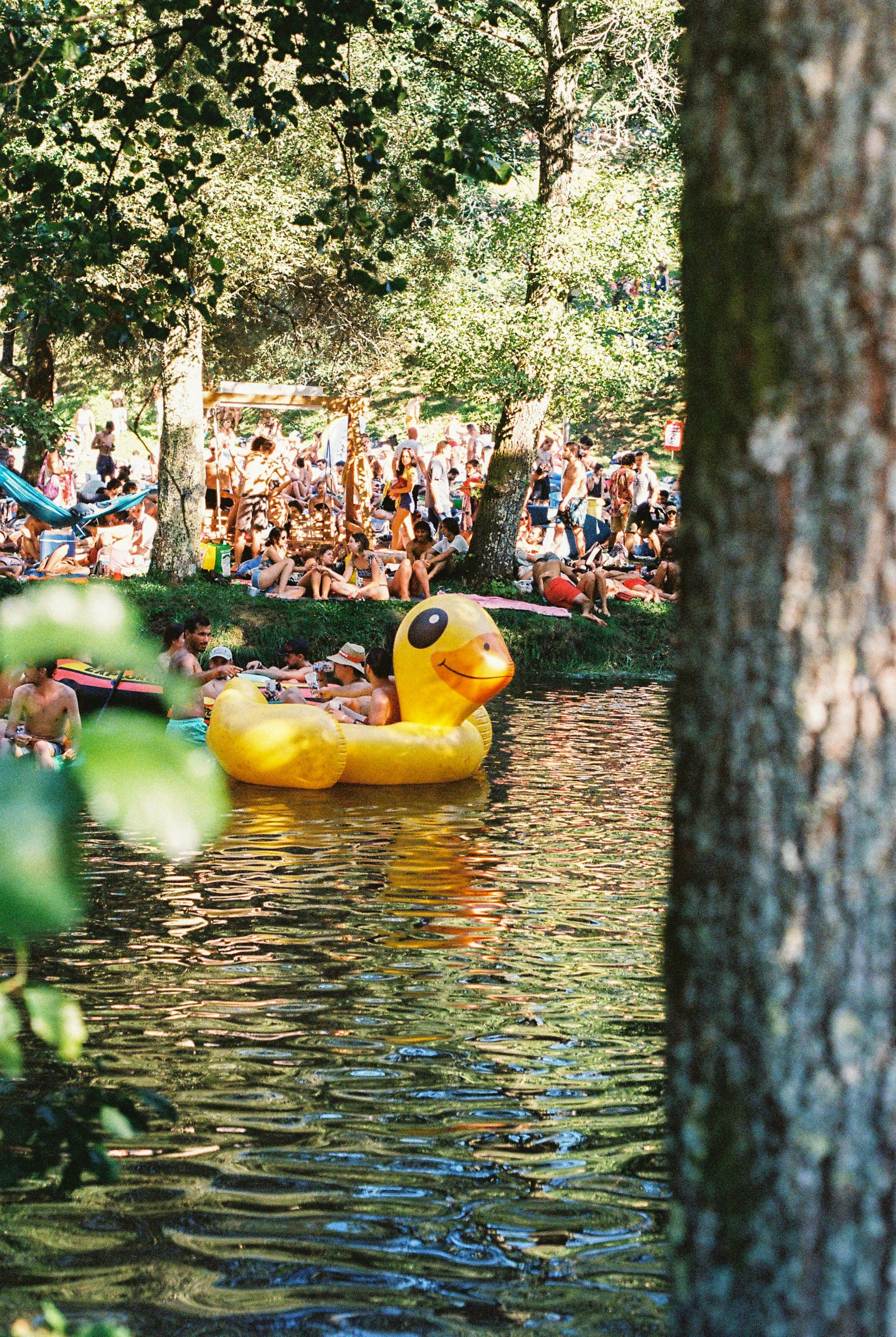 Duck pedal boat and crowd enjoying a sunny day by the river in Coura, Portugal.