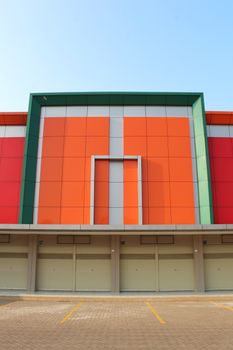 Symmetrical front view of a vibrant building exterior with closed garage doors and colorful panels. - Fotografer Sidoarjo