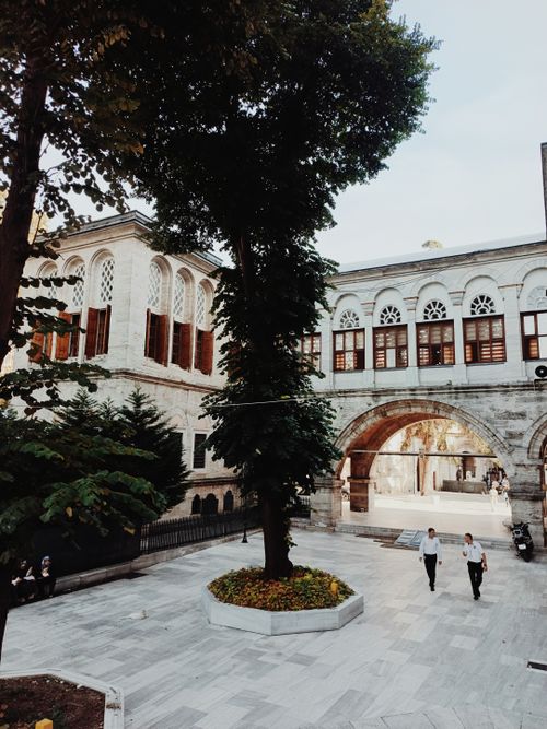 Free Elegant building facade with an arched walkway and courtyard garden. Stock Photo