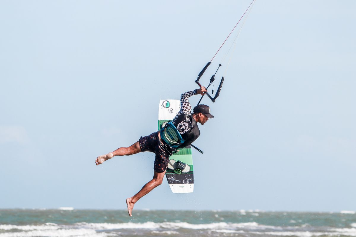 Kiteboarder performing a spectacular aerial jump over the ocean on a sunny day