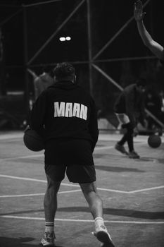 Black and white photo of a person playing basketball on an outdoor court at night in Moldova.