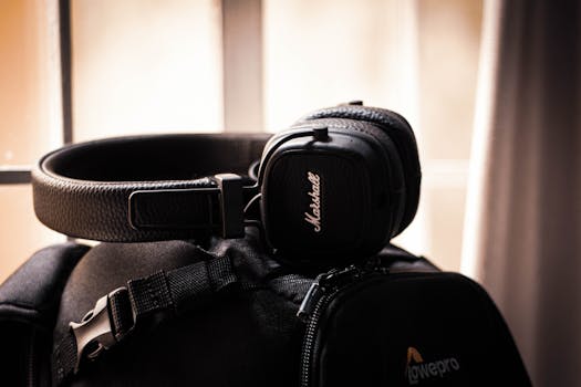 Close-up of black headphones placed on a travel bag by a window, creating a modern accessory vibe.