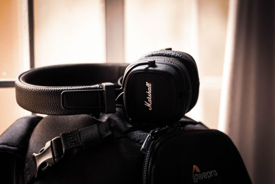Close-up of black headphones placed on a travel bag by a window, creating a modern accessory vibe.