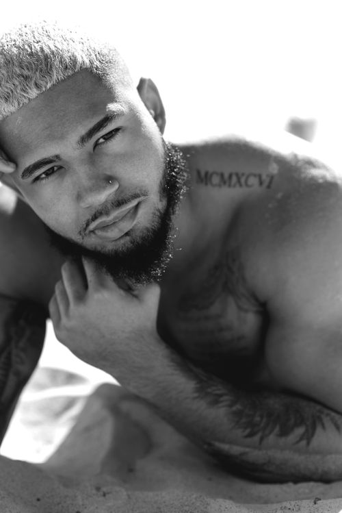 Free A contemplative black and white portrait of a shirtless man with facial hair, showing detailed tattoos and expressions. Stock Photo
