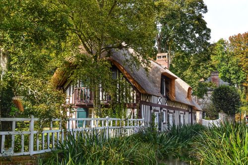 Free Idyllic countryside cottage surrounded by lush trees and greenery by the river. Stock Photo