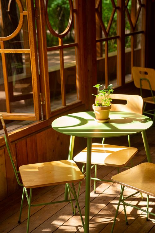 Boho café-style dining corner Café corner with green table and wooden chairs in a bohemian style