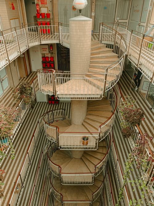Free A stunning view of a spiral staircase inside a modern building with metal railings and plants. Stock Photo