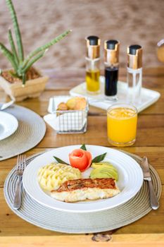 Delicious breakfast setting with fish, mashed potatoes, and fresh juice.
