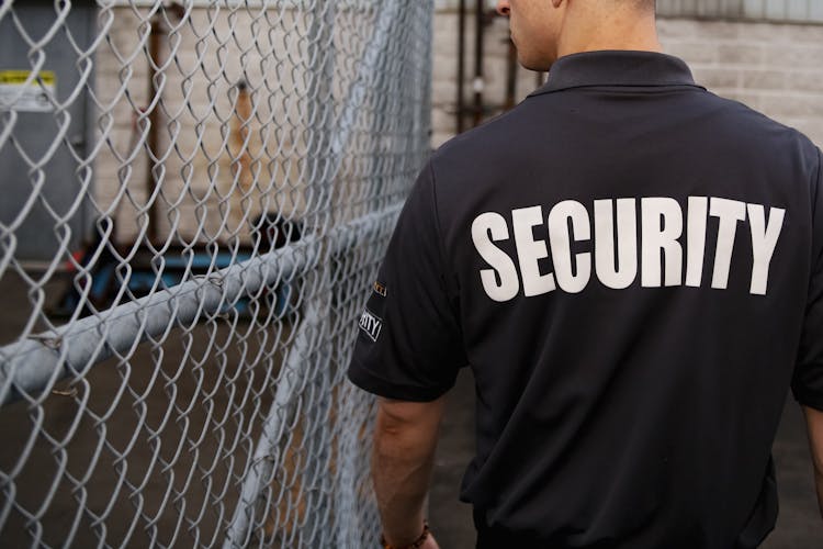 Security Guard Patrolling Near A Metal Fence