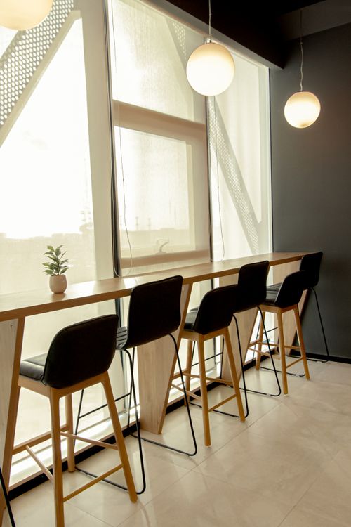Free Contemporary bar seating with sleek pendant lights and tall windows in Hyderabad, India. Stock Photo