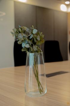 Elegant eucalyptus stems in a glass vase on a modern office table, creating a serene atmosphere.