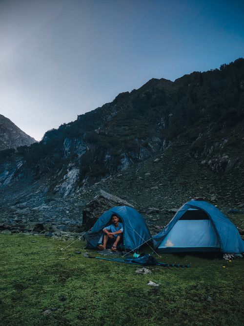 Free A camper enjoying a quiet moment by tents on a mountain landscape. Stock Photo