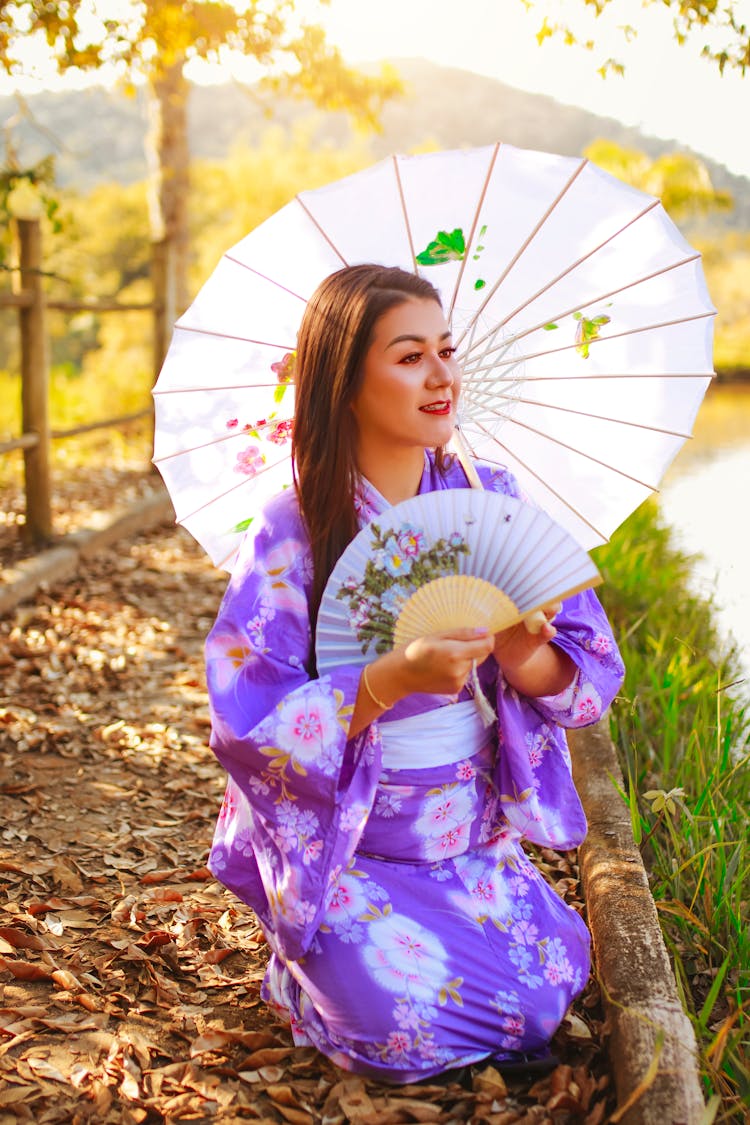 Woman Holding Umbrella And A Fan