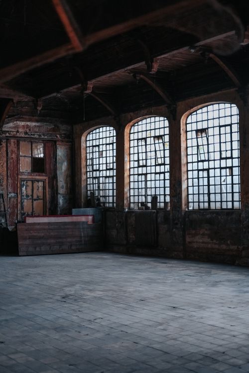 Free Interior of an abandoned industrial building with distinct arched windows and decay. Stock Photo