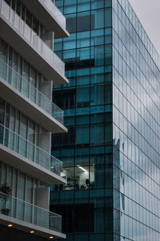 Urban scene showcasing modern architecture with glass skyscraper and adjacent balconies.