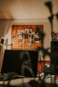 Warm creative workspace featuring a bulletin board with photographs and stacked furniture.