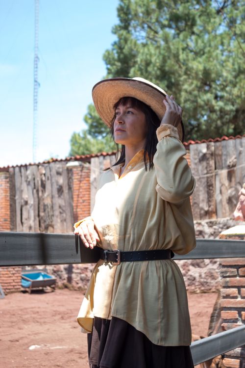 Free Woman in a sun hat standing by a fence outdoors, blending with the rustic surroundings. Stock Photo