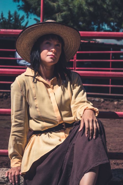 Free A woman in a straw hat rests outdoors, enjoying the sunny day in a relaxed pose. Stock Photo
