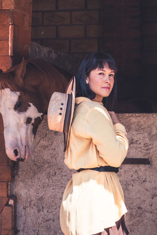 Free A woman in a stable, with a hat and horse, exuding a rustic charm. Stock Photo