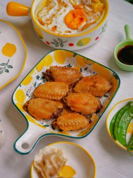 Close-up of gourmet fried chicken wings served with Asian cuisine on vibrant plates.