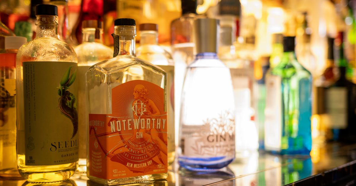 Vibrant display of various gin bottles on a polished bar counter with warm lighting.