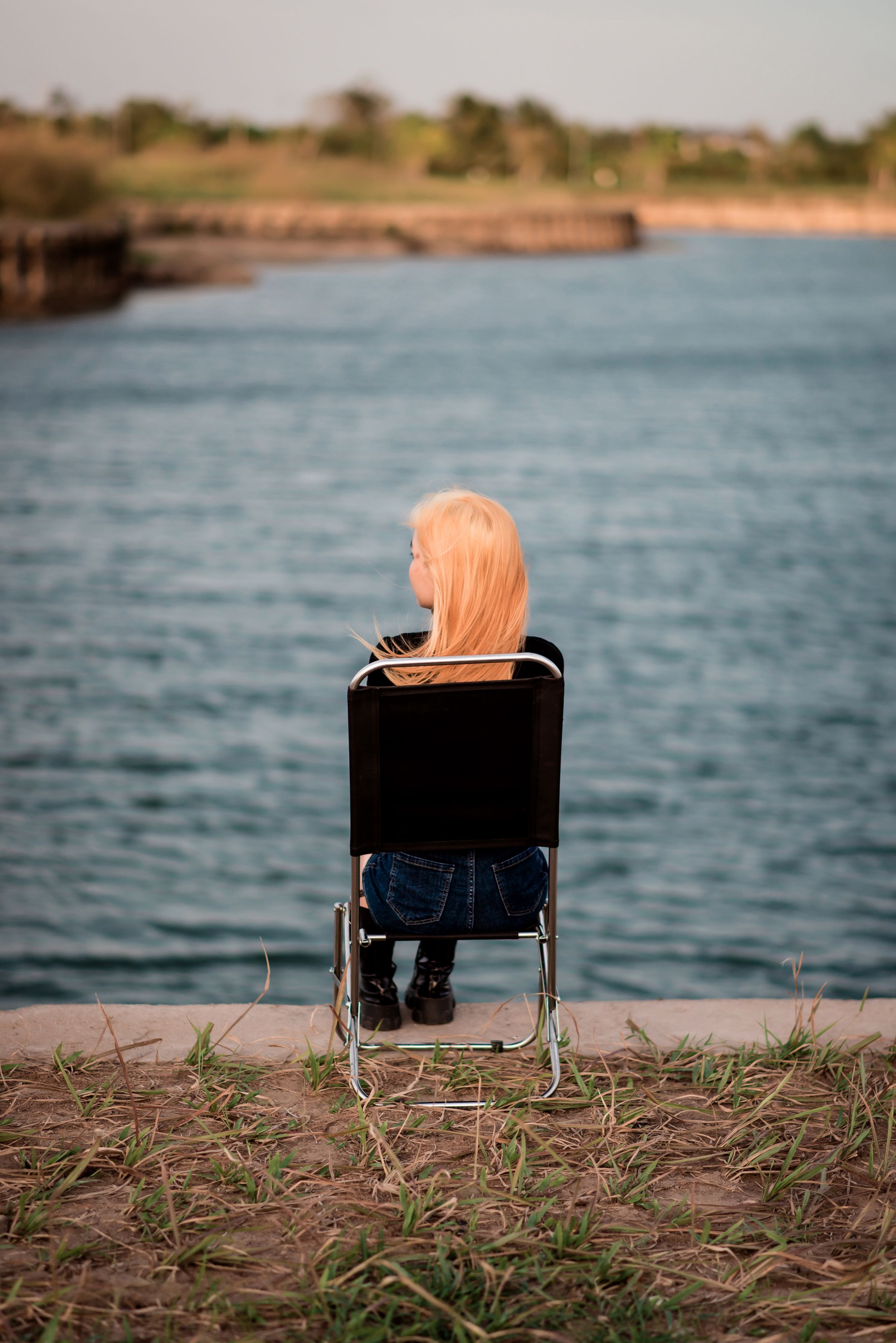 Blond Woman Sitting on a Chair near Body of Water · Free Stock Photo