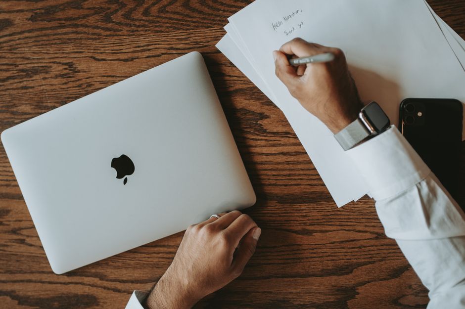 How Apple Watch Fall Detection Supports Elderly Parents Living Alone Top view of a desk with laptop and a person writing on papers with pen.