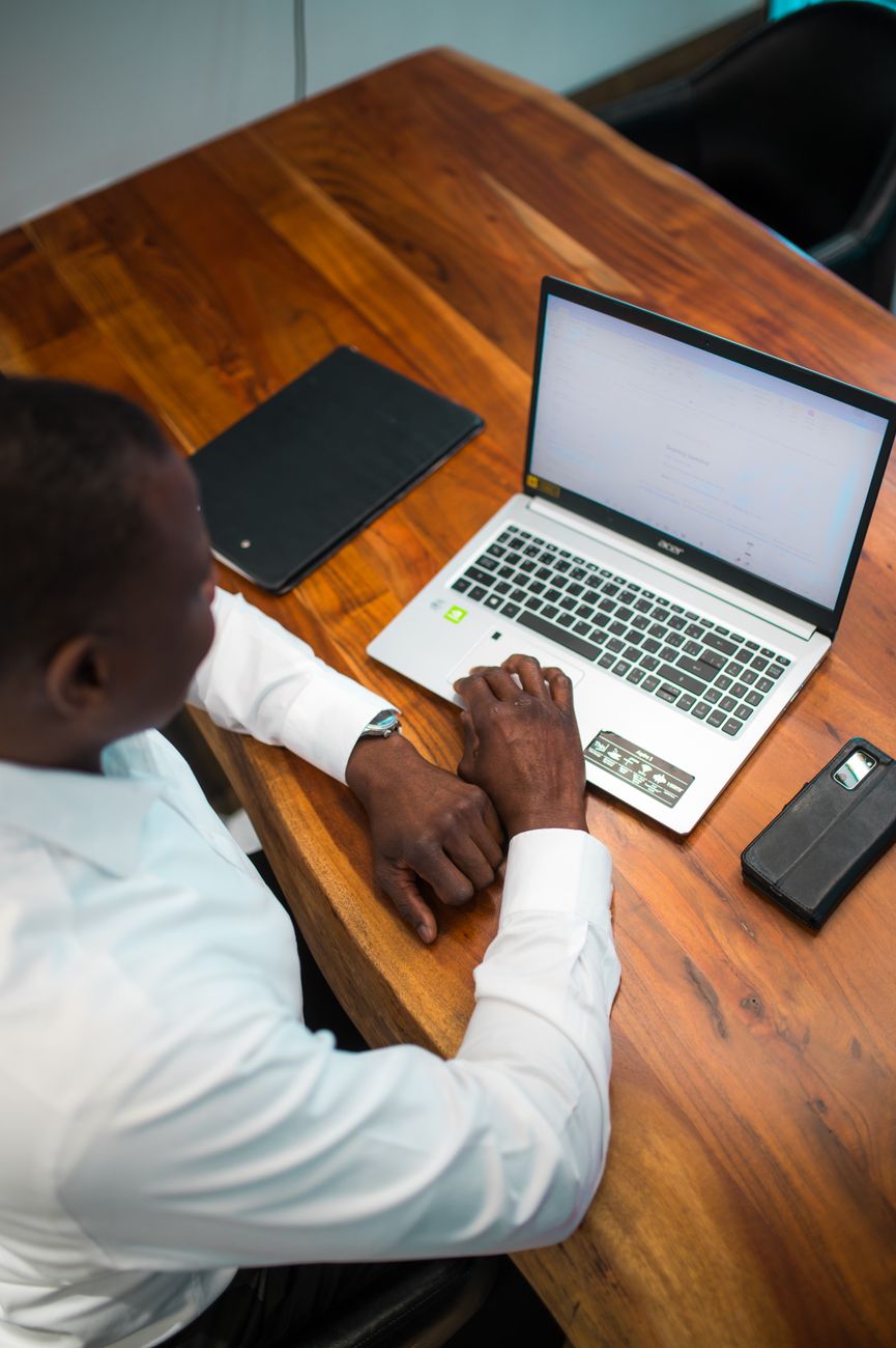 Businessman using a laptop at his wooden desk in an office environment.