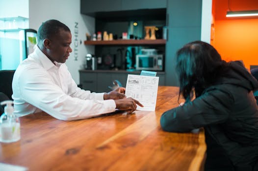 Business meeting between colleagues discussing a document indoors at a wooden table.