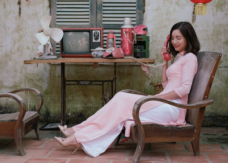 A Woman Sitting While Using Telephone 