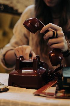 A close-up of hands dialing a vintage rotary phone.