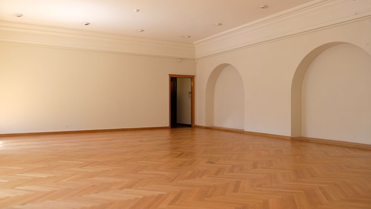 Large empty room with a newly laid wooden floor and arched doorways