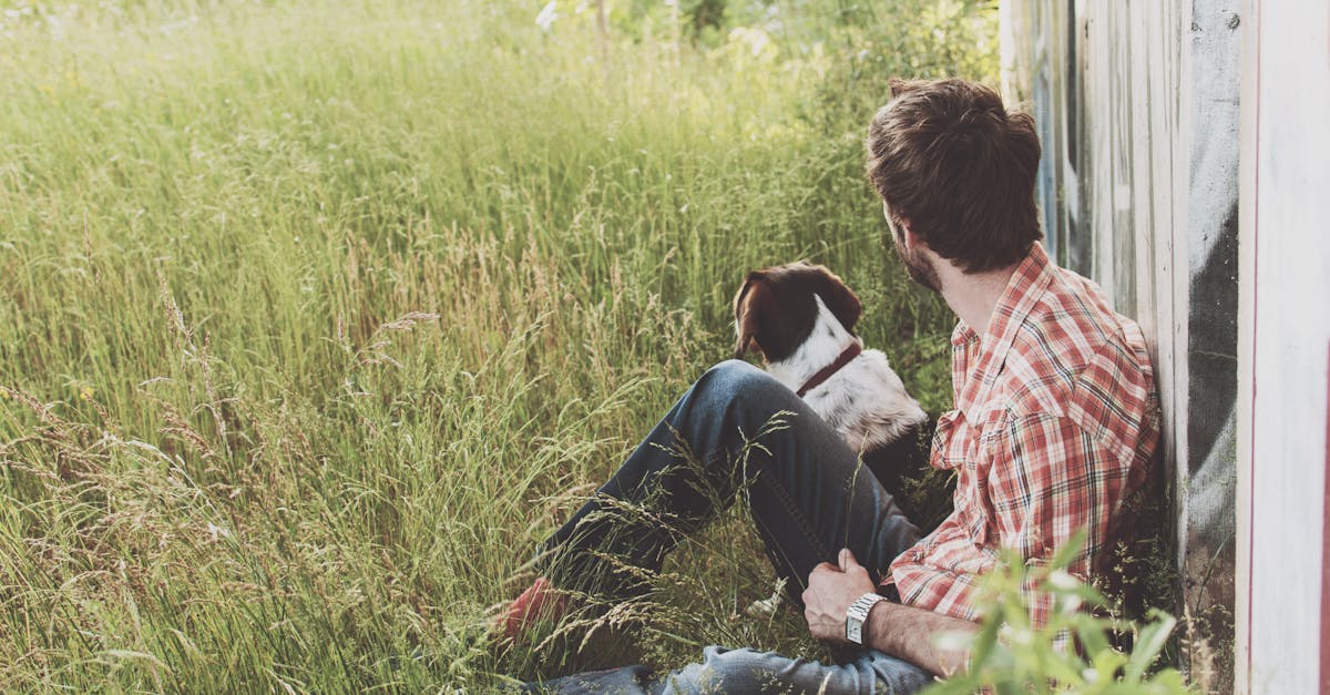 Man Sitting on Grass Beside Dog