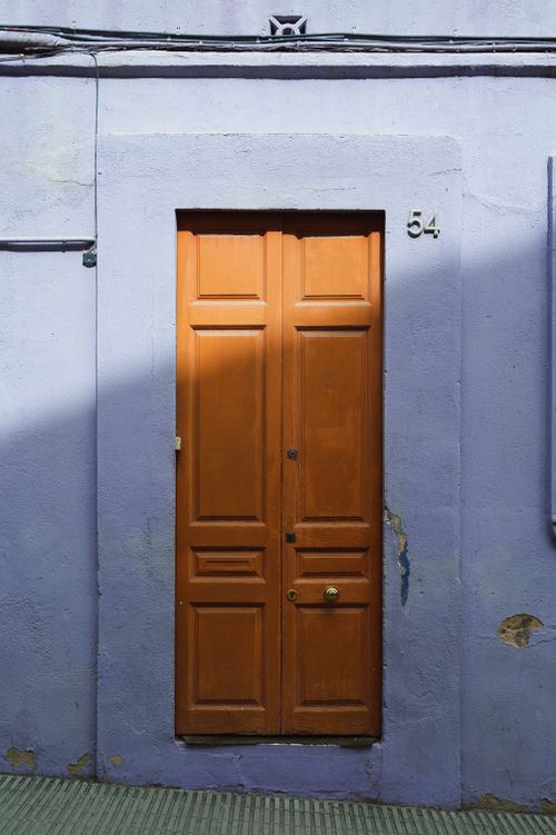 Free A rustic wooden door set in a textured wall with peeling paint and number 54. Stock Photo