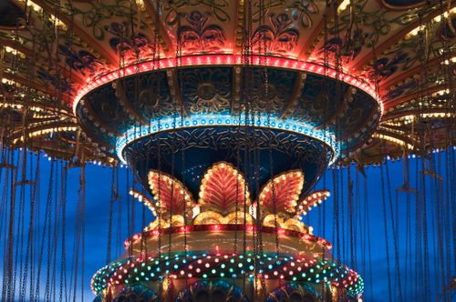 Free Vibrant lights illuminate a carousel at twilight in a bustling theme park. Stock Photo