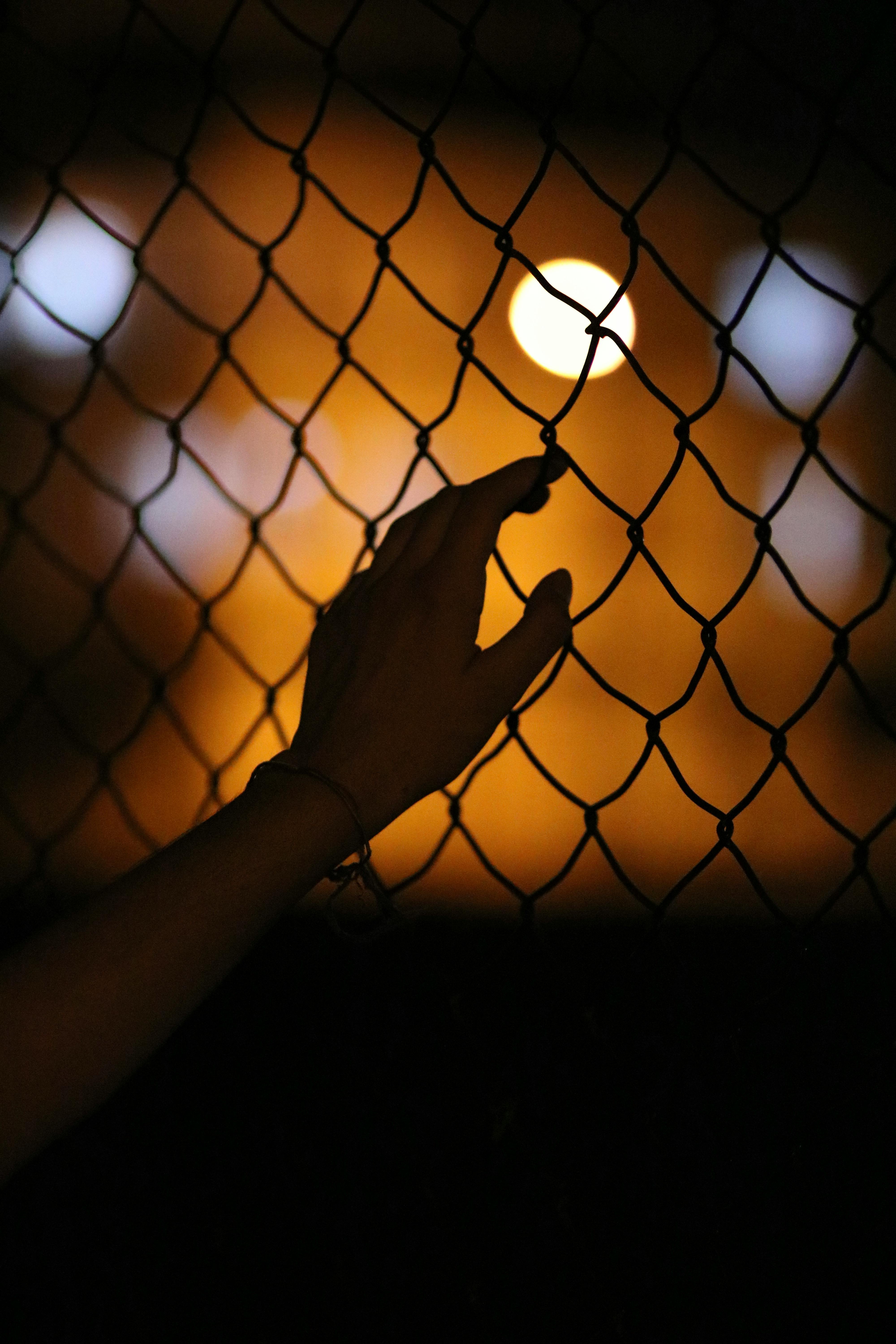 close up photo of hand on chain link fence
