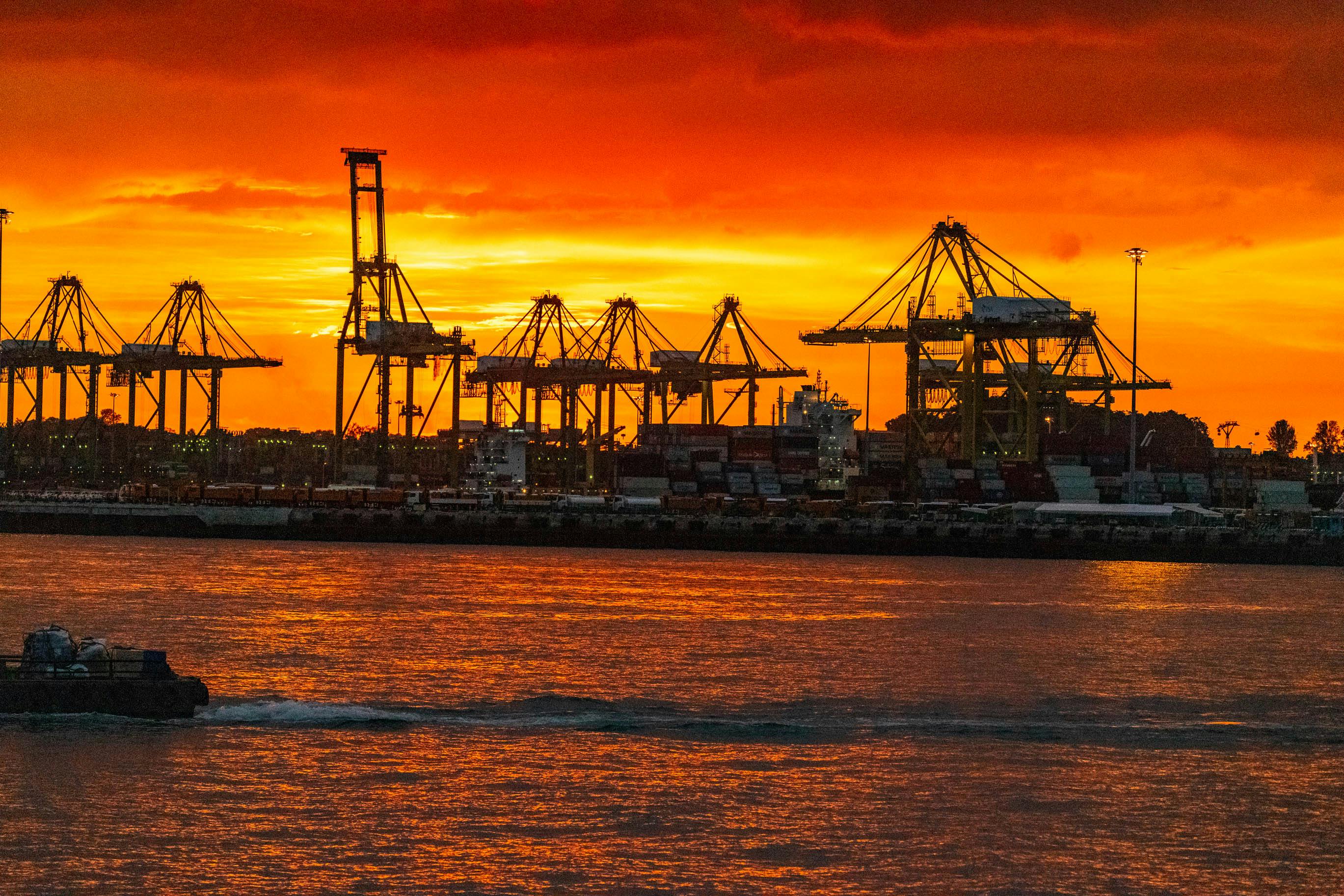 Buques portacontenedores en el puerto de Singapur con la silueta urbana al atardecer
