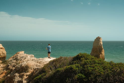 Person in Blue Shirt Standing near the Cliff 