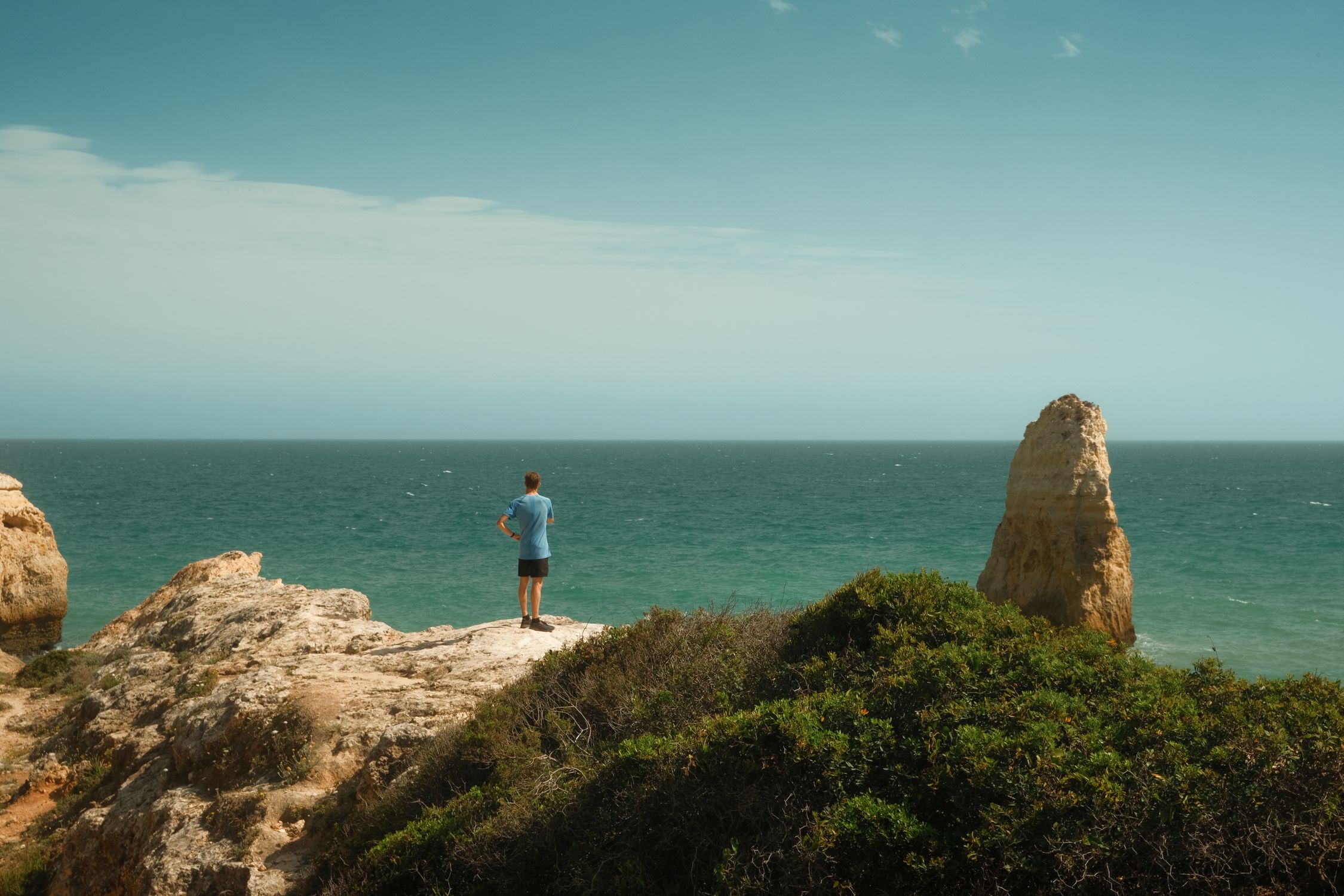 A traveler pauses on a clifftop overlooking the Atlantic on Portugal's coast.