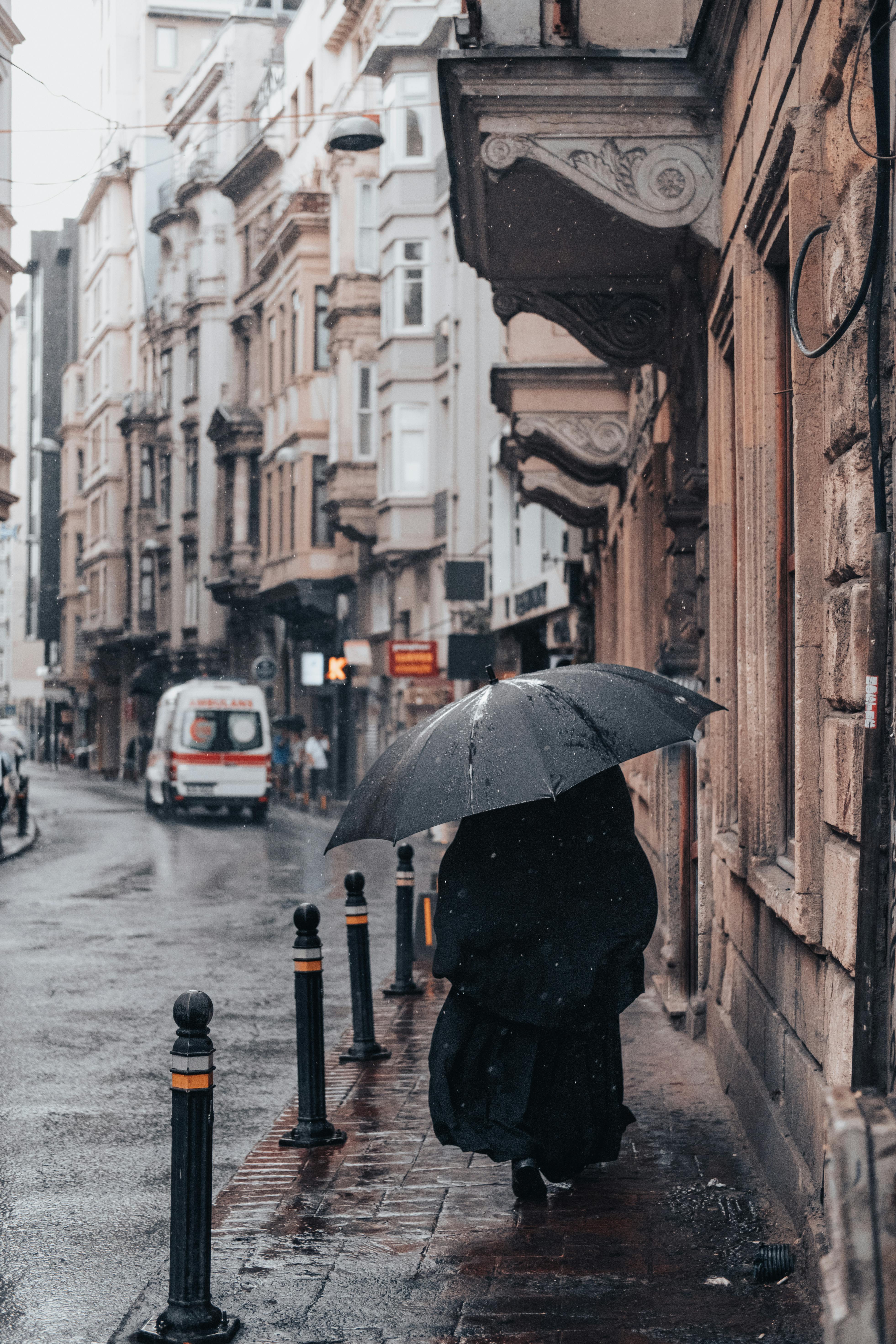 woman under umbrella walking old city street