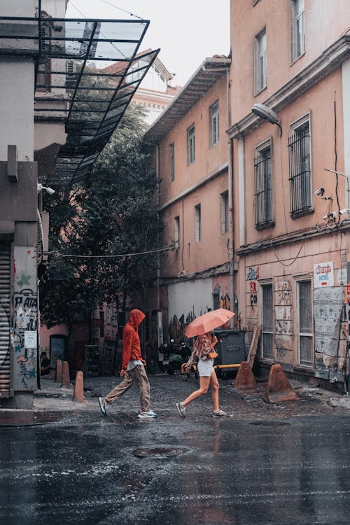 People Walking on the Wet Road Near the Buildings