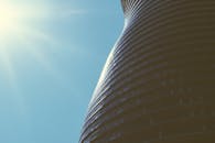 现代摩天大楼的弧形设计映衬着清澈的蓝天和耀眼的阳光