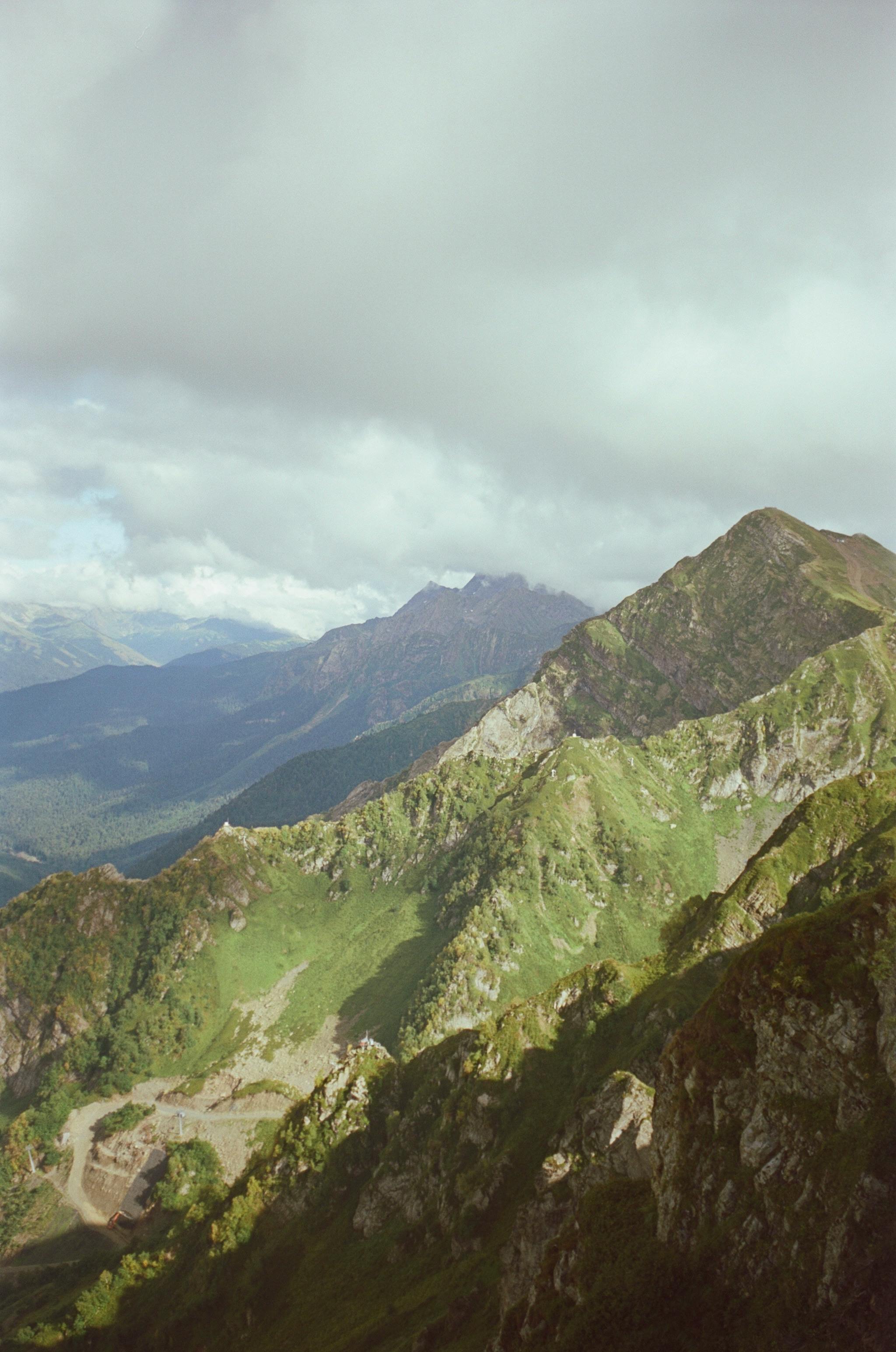 Captivating photo of green and rocky mountains under a cloudy sky, showcasing natural beauty.